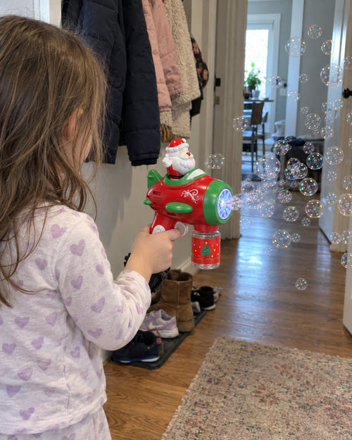 Child holding the Santa Bubble Gun with bubbles in a hallway